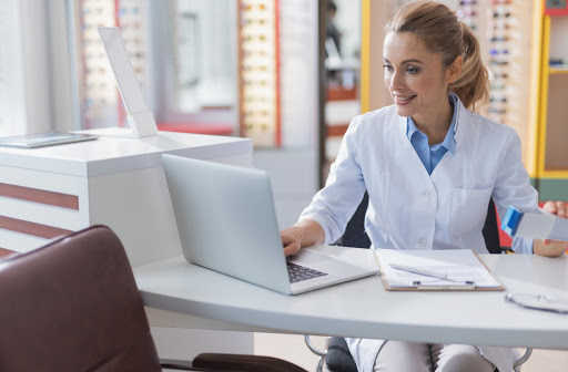 Optometrist smiling and using electronic medical records software at an optometry clinic.
