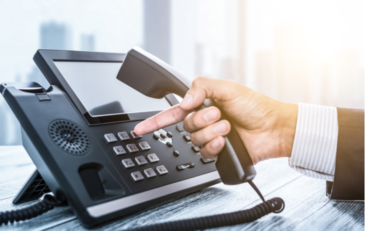 Close up of hand reaching for telephone to contact patient regarding appointment