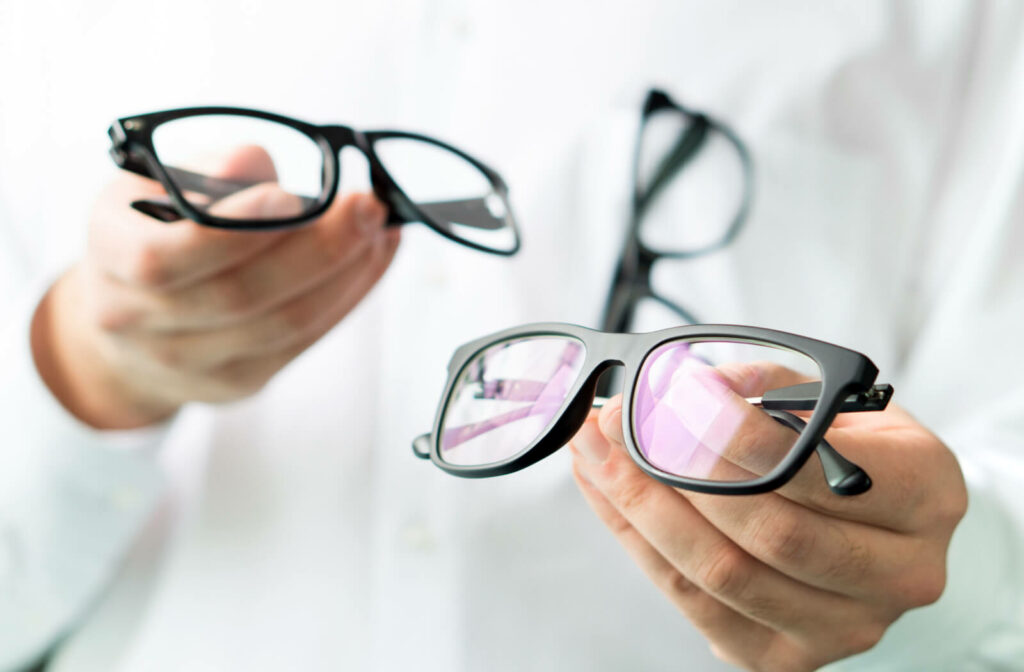 an optometrist holding two pairs of glasses