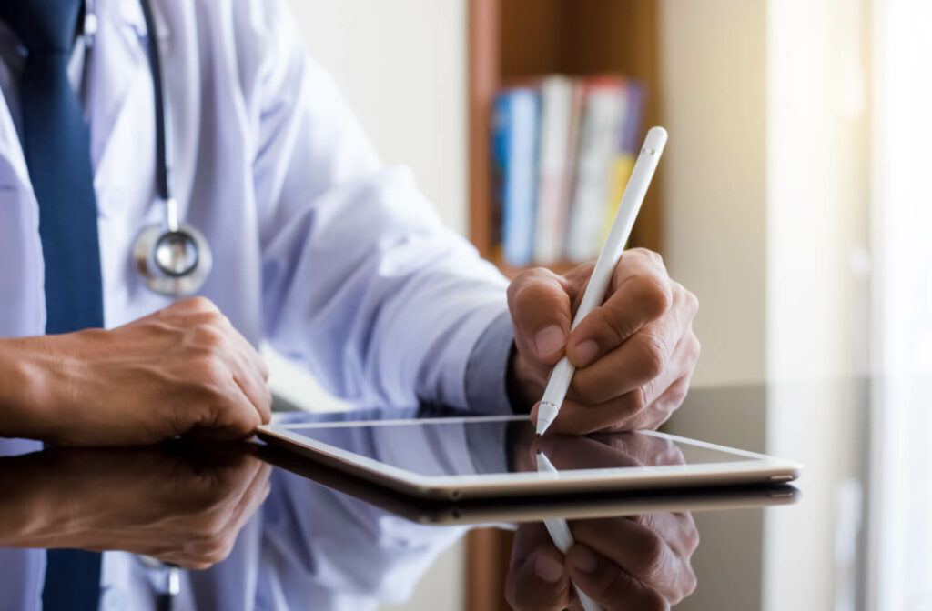 close up of a doctor using an apple stylus on a tablet to update electronic medical records